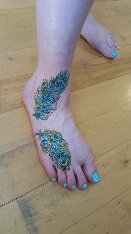 Glitter henna peacock feathers on the tops of both feet