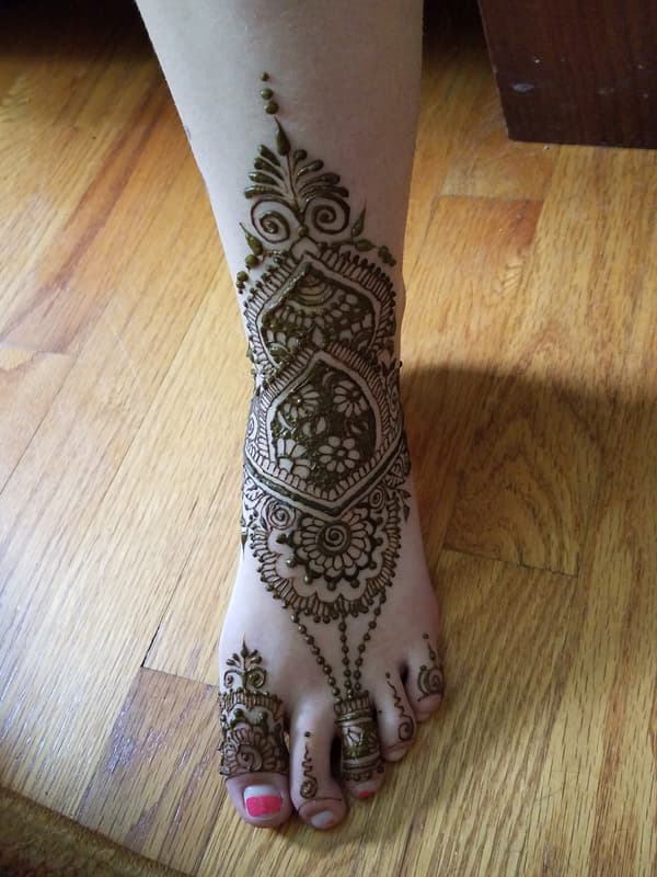 Traditional henna design covering the top of a foot, ankle and toes