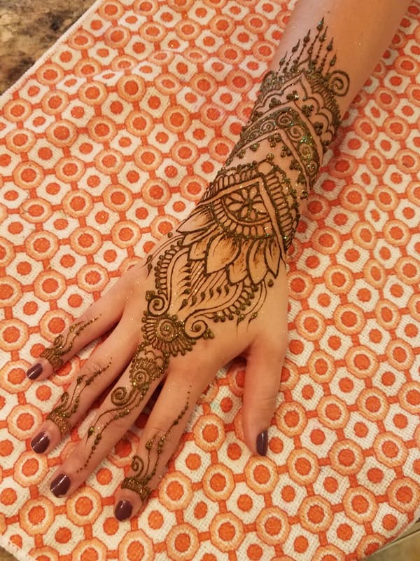 Glittered henna lotus and cuff covering a hand and wrist