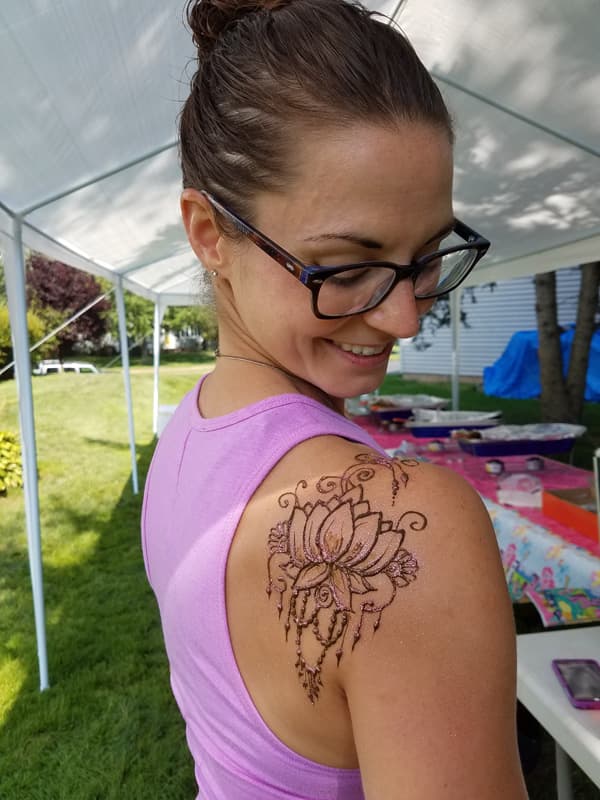 Guest at a garden party with a glittered henna lotus on her shoulder