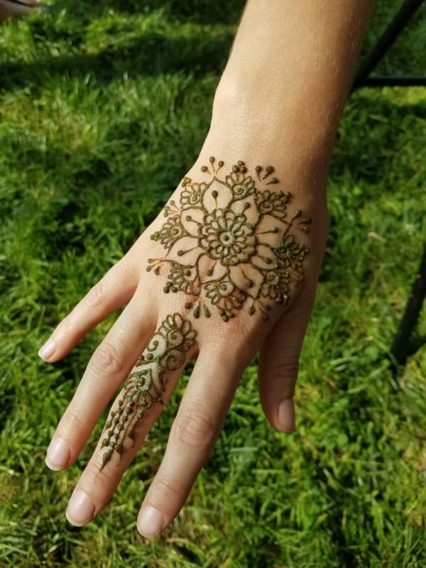 Henna flower burst on the back of a hand, photographed on the grass