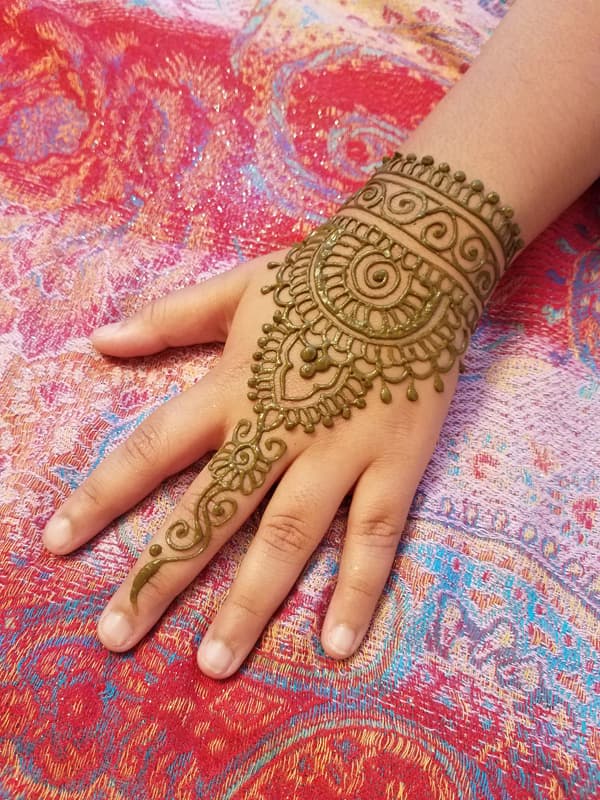 Henna cuff and fan medallion with a curling vine down one finger
