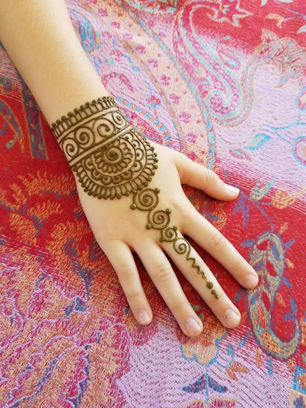 Scalloped henna cuff with a spiral chain draping over the back of a hand