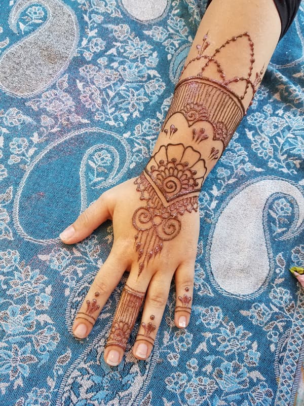 Shell and cuff henna design reaching from the fingers up over the wrist