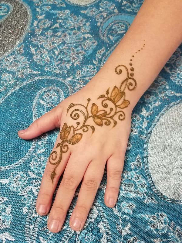 Delicate henna lotus vine trailing across a child's hand