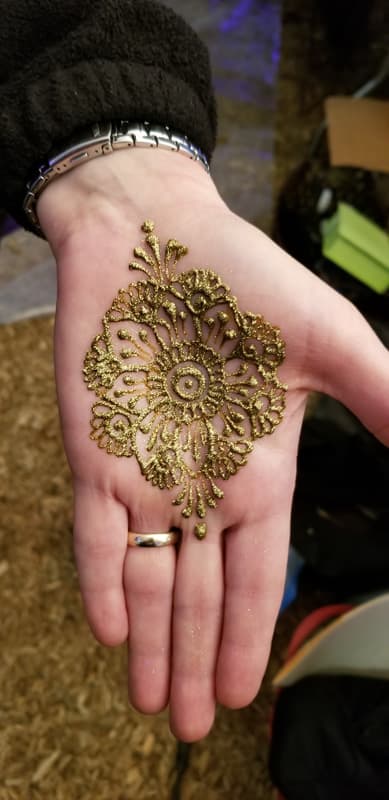 Gold glitter henna flower centred on an open palm