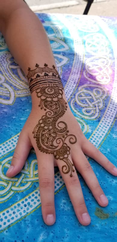 Henna cuff and paisley swirl design flowing down the back of a child's hand