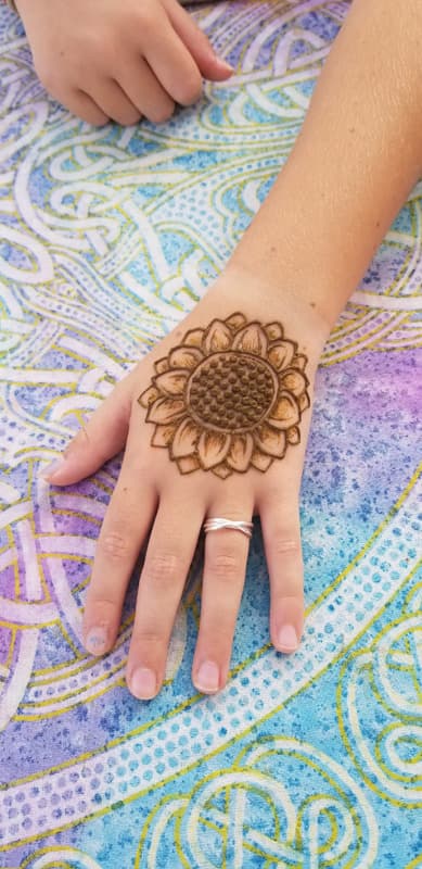 Henna sunflower centred on the back of a child's hand