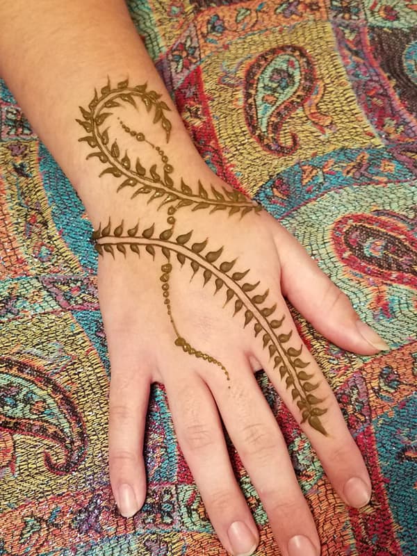 Leafy henna vine wrapping around the wrist and down one finger
