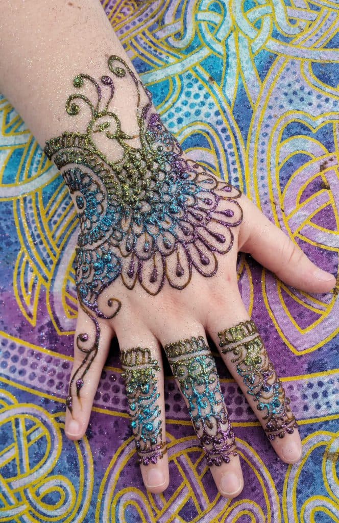 Intricate hand-drawn henna design across the back of a hand