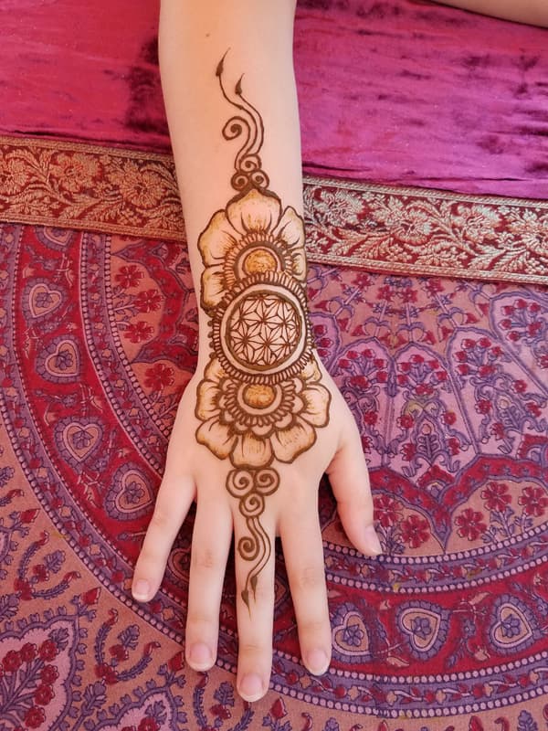 Henna flower and sacred geometry medallion running from the wrist across the hand